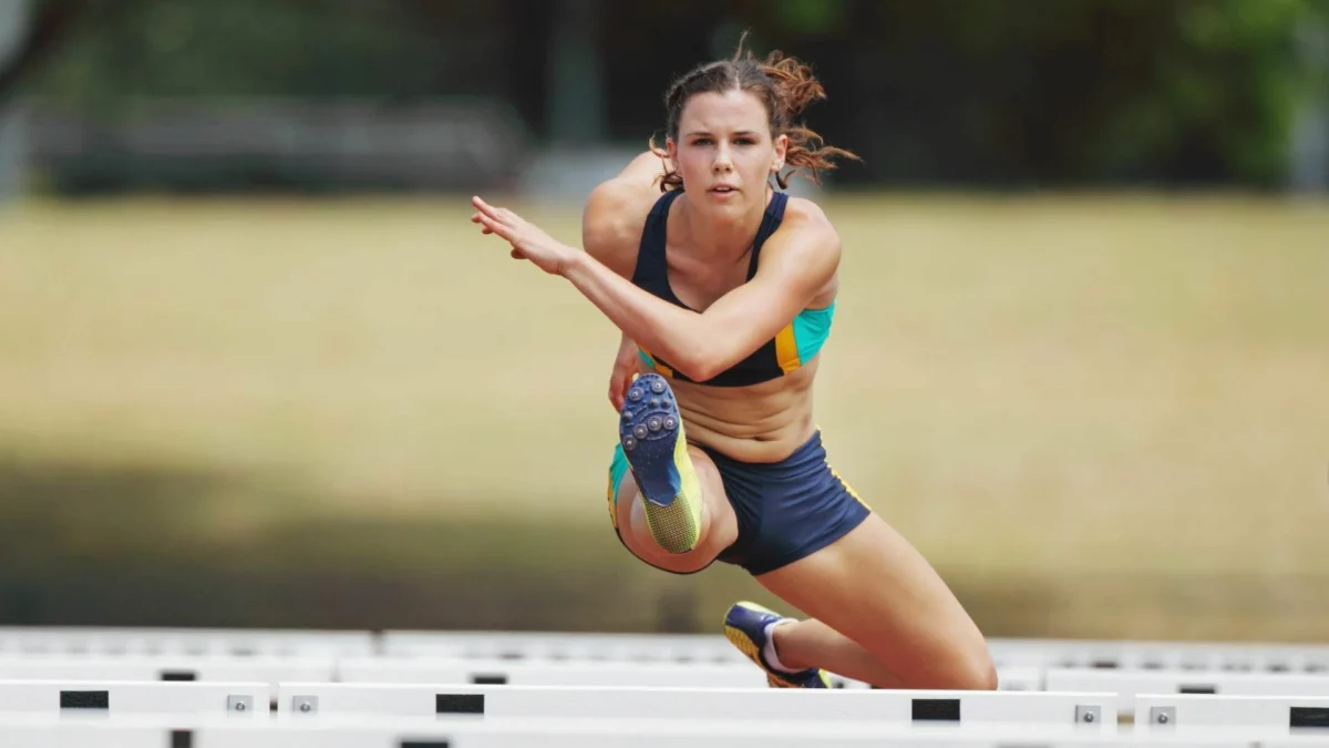 This image shows a woman practicing a hurdle, illustrating the concentration and mental performance required for athletic discipline.